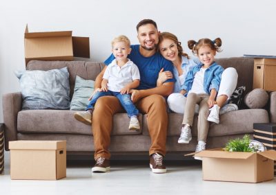 family sitting on a couch with packing boxes around them